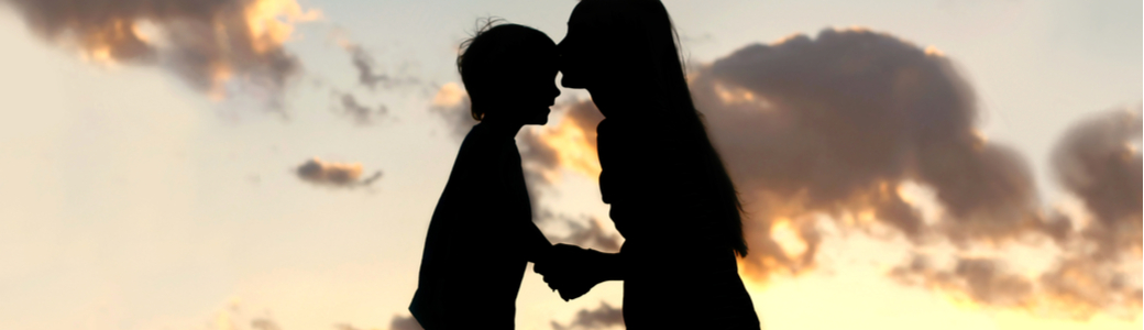 Silhouette of mother kissing her son on the head