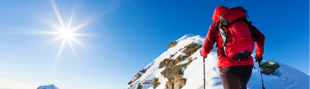 A climber at the top of a snowy peak.