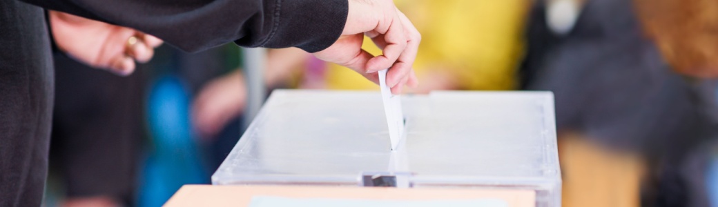 A man voting using a ballot box.