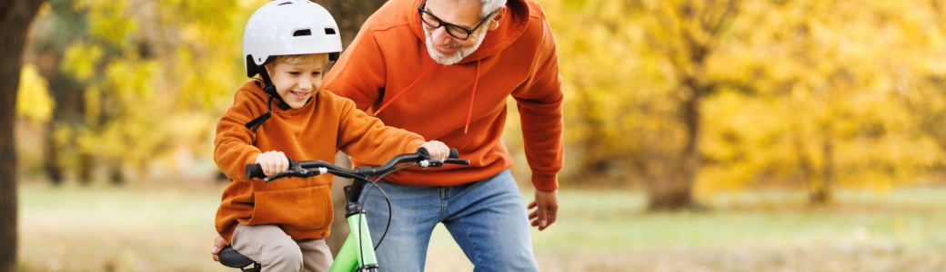 A man teaching his grandson to read a bike.
