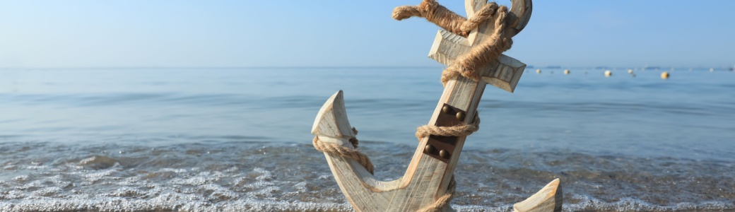 A wooden anchor on a beach.