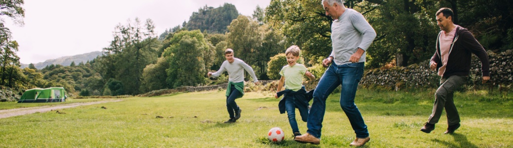 Multi-generational family playing football in a park.