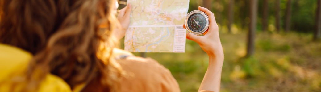 A young woman hiking and using a compass.