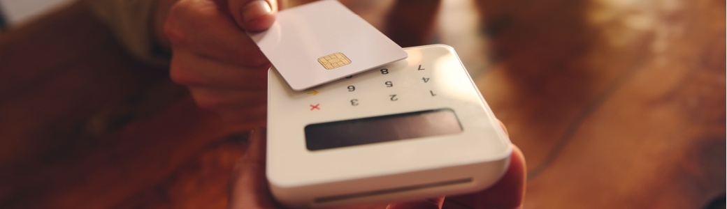 A person using their debit card to pay in a café.