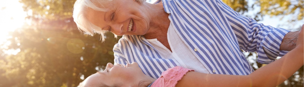 A grandmother playing with her granddaughter outside.